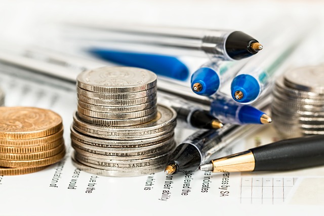 Monedas apiladas y bolígrafos sobre documentos financieros, representando servicios de asesoría en Legazpi